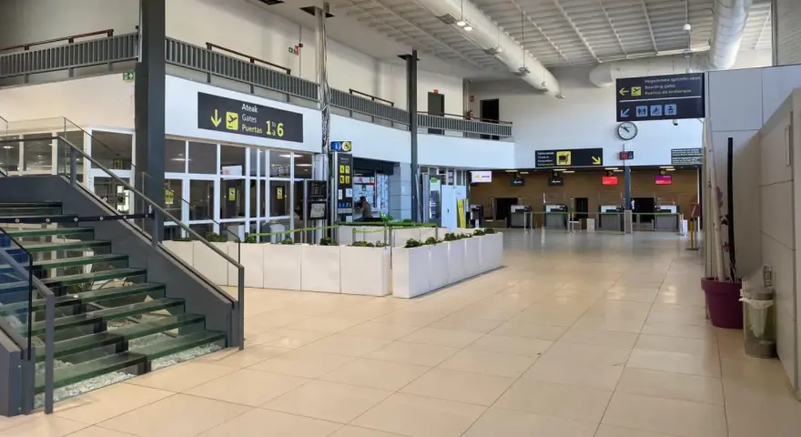 Inside an airport terminal, signs point to boarding gates 1-6. This is likely the closest airport to San Sebastian.