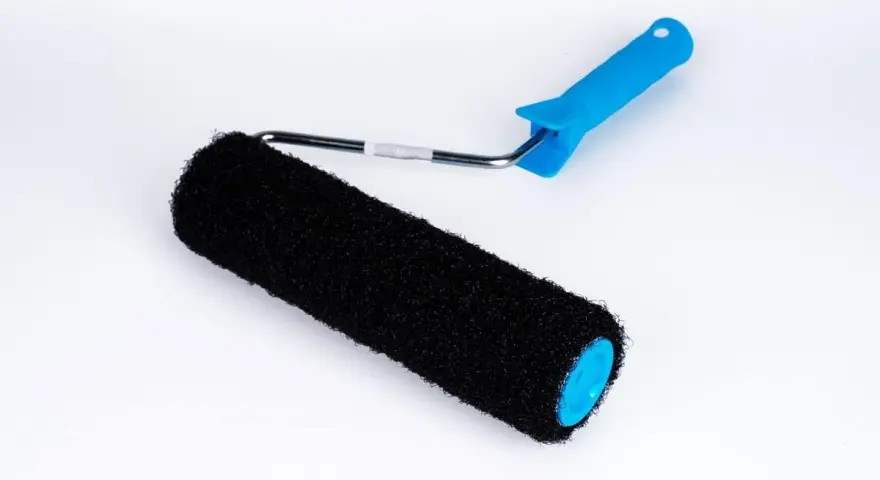En svart roller med blått handtag, perfekt för att applicera rullspackel jämnt på väggar.