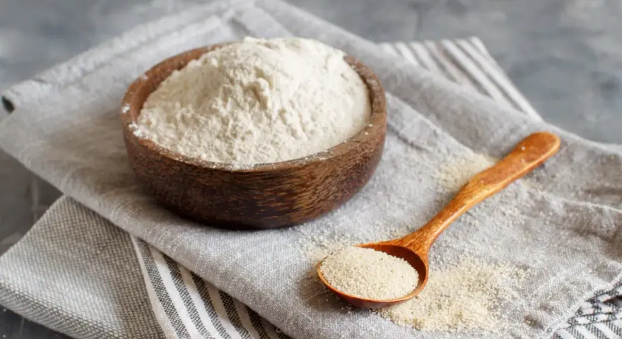 Mąka gryczana w drewnianej misce i na łyżce. Czy mąka gryczana ma gluten? Nie, jest bezglutenowa.