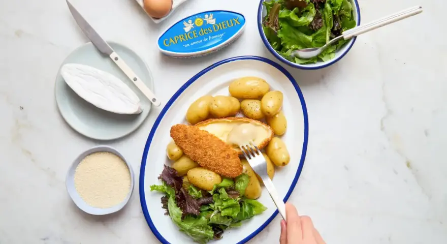 Délicieuse recette Caprice des Dieux pané, servi avec des pommes de terre et une salade verte. Le fromage coulant est irrésistible !