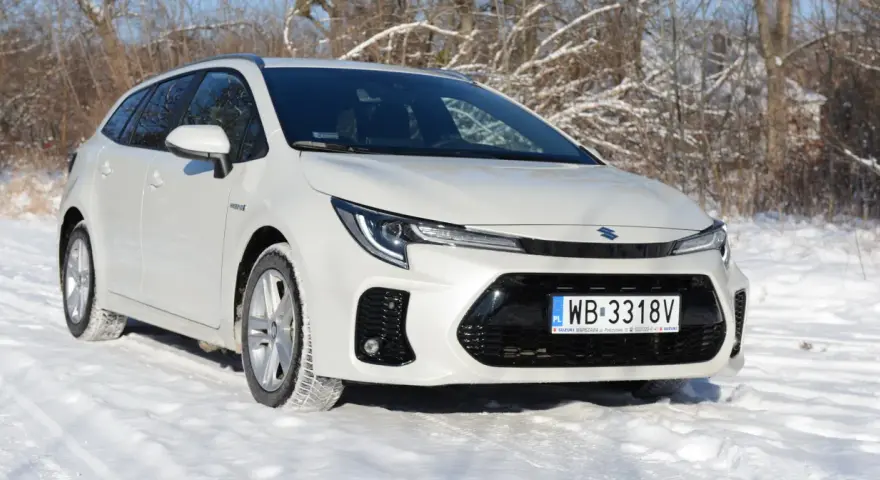 Biały Suzuki Swace Hybrid na śniegu, gotowy na zimowe wyzwania.