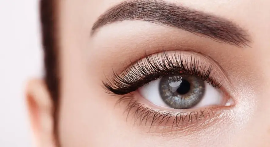 Ojo de mujer con pestañas largas y cejas definidas. Descubre cómo hacer crecer las pestañas para una mirada impactante.