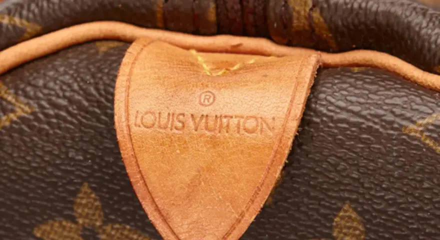 Etichetta in pelle con logo Louis Vuitton, un dettaglio iconico che evoca la maestria della fabbrica Louis Vuitton.