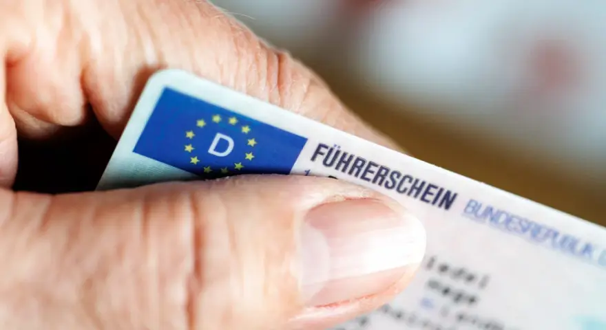 Nahaufnahme eines Führerscheins, der von einer Hand gehalten wird. Die Person könnte versucht sein, trotz Fahrverbot zu fahren.