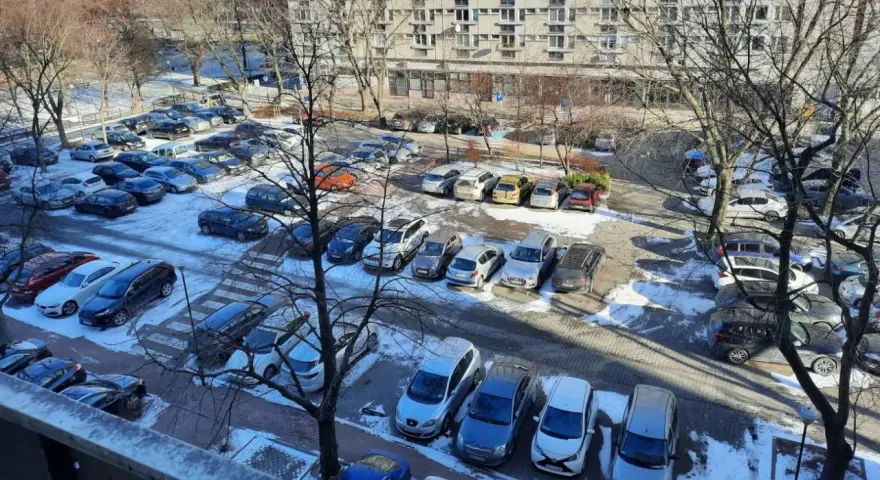 Zimowy parking pod blokiem z lat 90. pokazuje, dlaczego mieszkańcy mają problem z parkowaniem. Auta upchnięte na każdym wolnym skrawku ziemi.