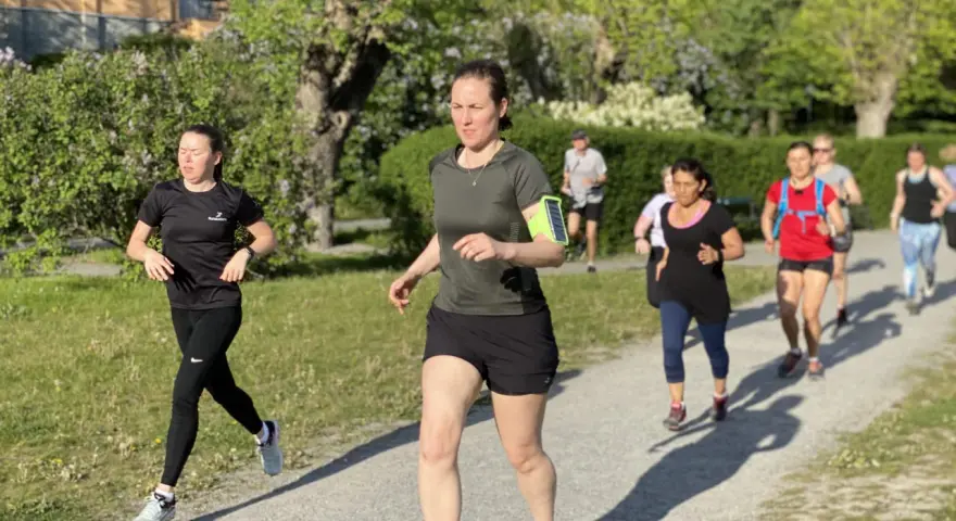 En grupp löpare på en grusväg, en del med fokus på att få upp konditionen snabbt. Solen skiner och träden är gröna.