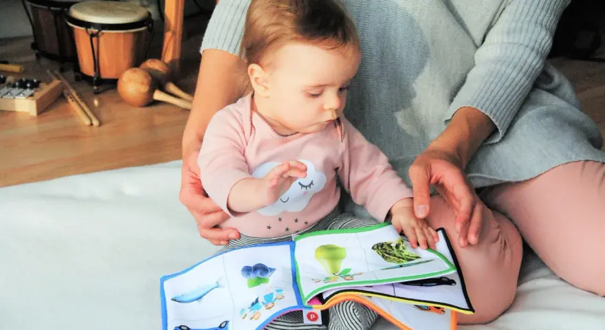 Baby lernt mit einem Stoffbuch und Musikinstrumenten. Förderung der sprachentwicklung baby.