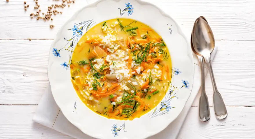 Aromaticzna zupa koperkowa z ryżem, marchewką i kawałkami kurczaka, udekorowana świeżym koperkiem.