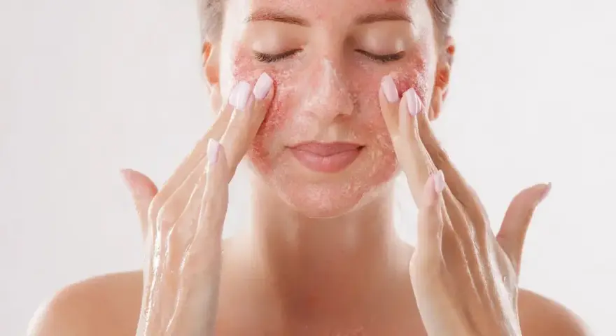 Kobieta z zamkniętymi oczami delikatnie masuje twarz, aplikując produkt z drobinkami. To może być skuteczny retinol na zaskórniki, który odnawia skórę.