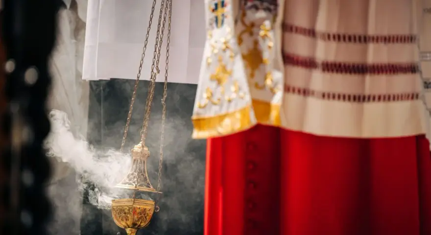 Złota kadzielnica unosi dym podczas uroczystości. W tle widać szaty liturgiczne, przypominające o święta nakazane.