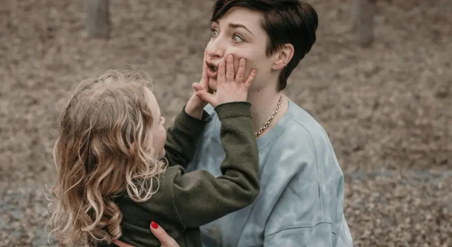 Kind drückt der beleidigten Mutter die Wangen zusammen.