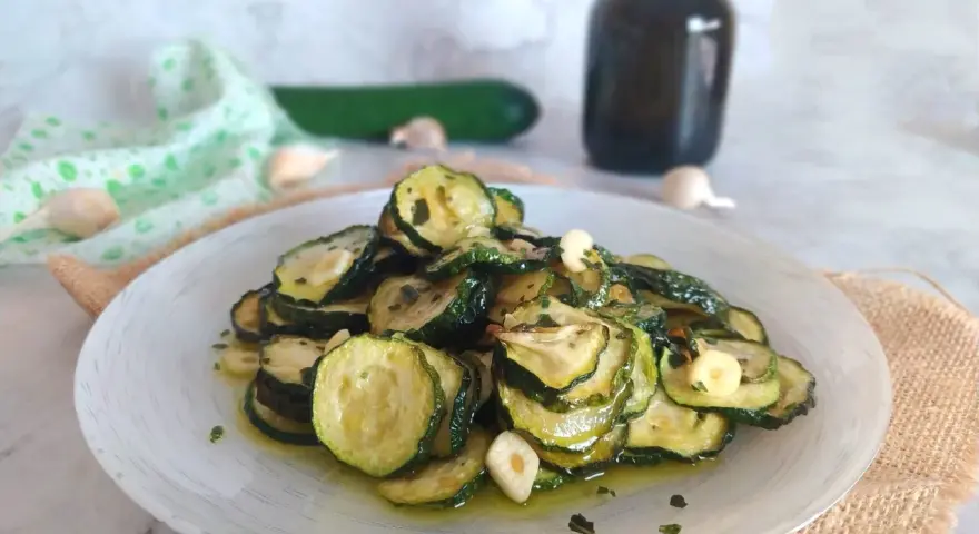 Piatto di zucchine alla scapece, fette sottili condite con olio, aglio e prezzemolo.