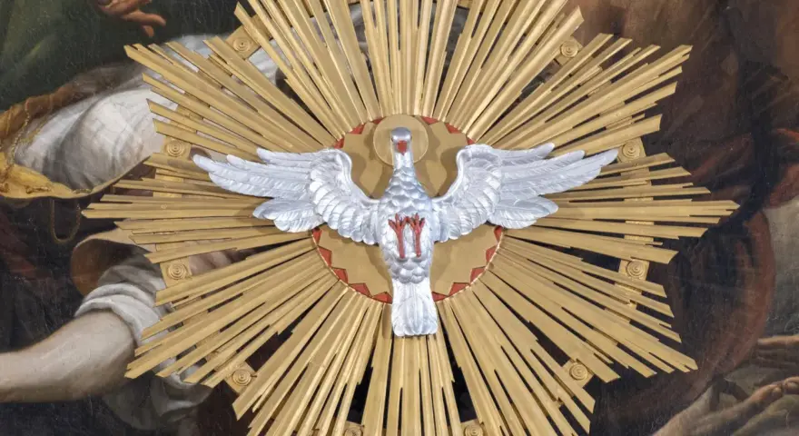 Ein silberner Taube mit ausgebreiteten Flügeln vor einem goldenen Strahlenkranz. Dies symbolisiert den Heiligen Geist und was bedeutet Pfingsten: die Ausgießung des Geistes.