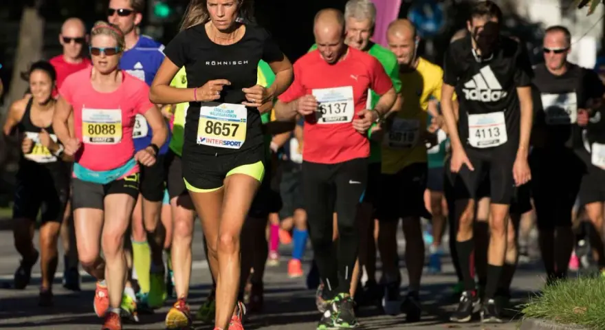 Kvinnlig löpare i täten under Stockholm tempo halvmaraton. Många löpare i olika färger på kläderna.