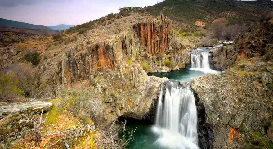 Cascadas en el río Guadalajara, rodeadas de rocas rojizas y vegetación otoñal.