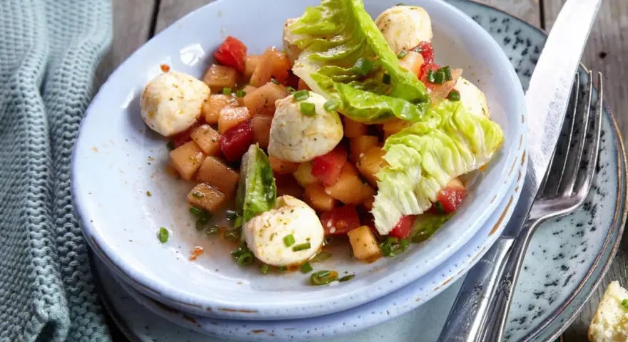 Erfrischender melonensalat mit mozzarella, Tomaten und knackigem Salat. Ein leichter Genuss für warme Tage.