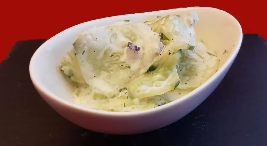 Salade fraîche de concombre à la crème, parsemée d'herbes fines. Un délice léger et savoureux.