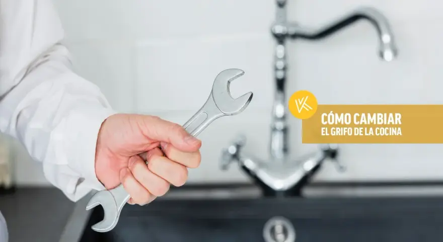 Mano con llave inglesa lista para instalar grifo cocina. Texto: "Cómo cambiar el grifo de la cocina".