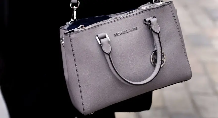 Szara torebka Michael Kors, znanej firmy z luksusowymi akcesoriami, z widocznym logo.