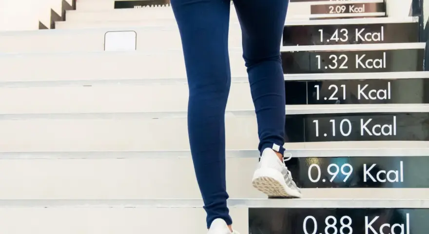 Personne montant des escaliers, chaque marche indiquant les calories brûlées. Une heure de marche pour brûler des calories.