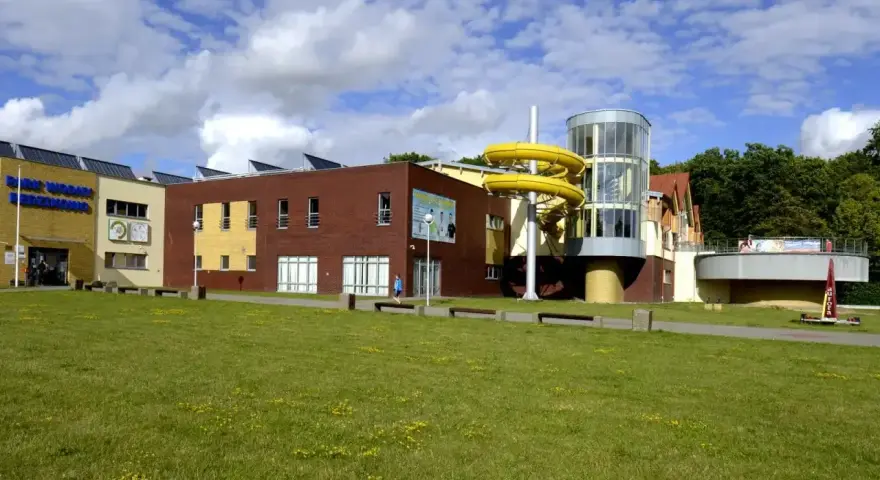 Park Wodny w Redzikowie z żółtą zjeżdżalnią i zielonym trawnikiem.