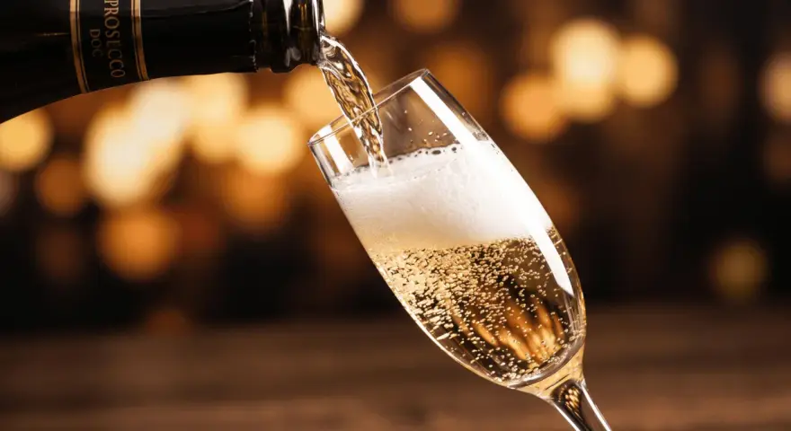 Bąbelki musującego prosecco wypełniają kieliszek, gdy jest nalewane z butelki. To jest właśnie to, co to jest prosecco – włoskie wino musujące.