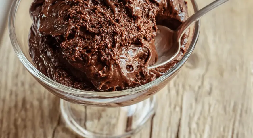 Une cuillère s'enfonce dans une coupe de mousse au chocolat au lait onctueuse, prête à être dégustée.