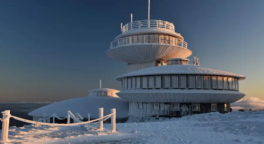 Lodowy pałac na szczycie w Karkonoszach. Budynek obserwatorium pokryty szronem, otoczony zimowym krajobrazem.