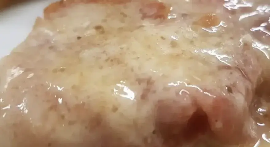 Cotoletta alla bolognese succulenta, con prosciutto e formaggio fuso, un classico della cucina emiliana.