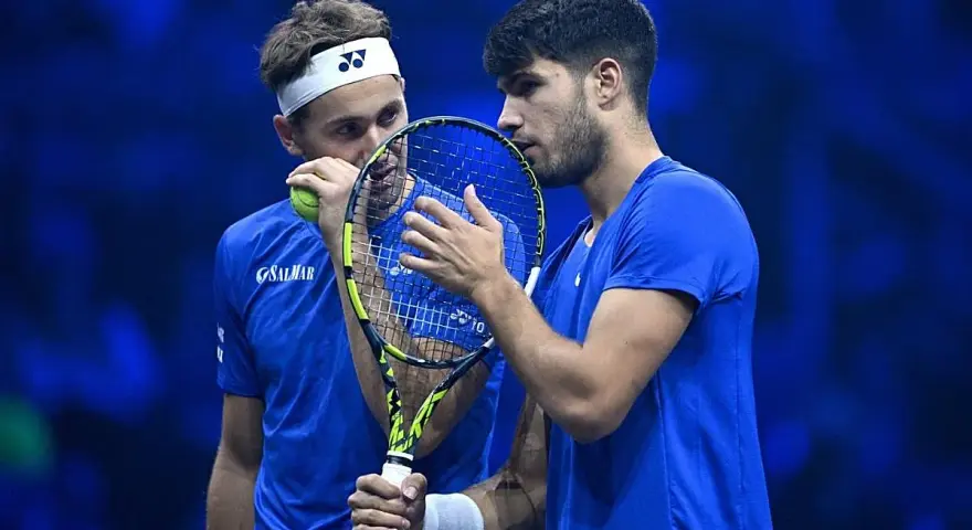 Carlos Alcaraz y Casper Ruud, dos tenistas en un momento de concentración, con raquetas y pelota.