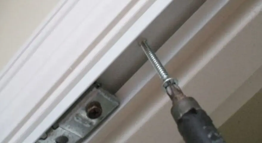 Screwdriver installing a bracket for how to install bifold doors.