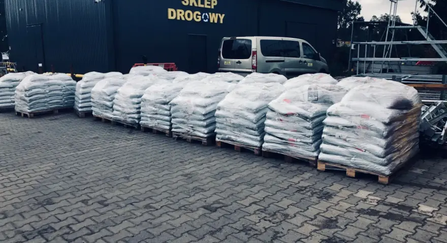 Duże worki z materiałem budowlanym przed sklepem drogowym. Zastanawiasz się, ile kosztuje asfalt? Tutaj znajdziesz odpowiedź.