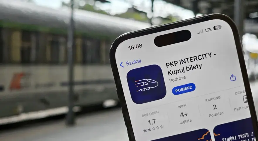 Telefon z aplikacją PKP Intercity na tle pociągu.