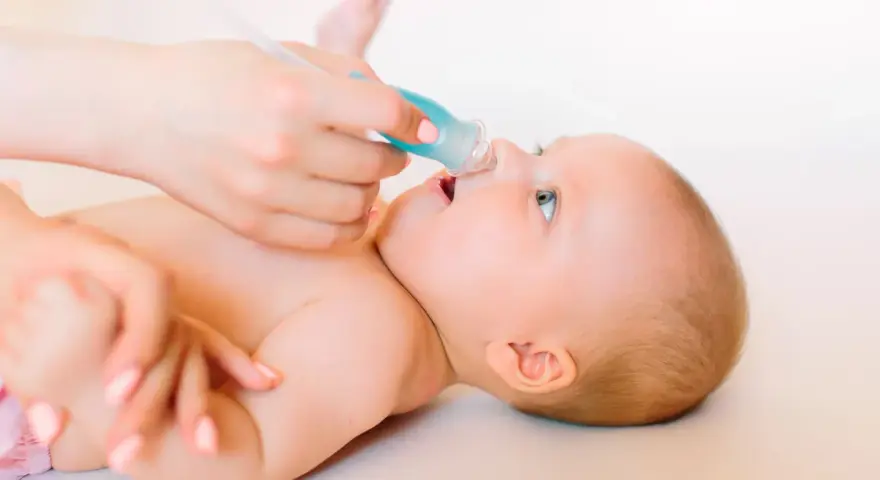 Manos cuidadosas realizan lavado nasal a un bebé.