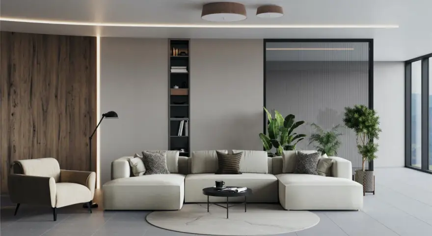 Un ampio divano modulare, perfetto per un soggiorno open space, con poltrona, libreria e piante.