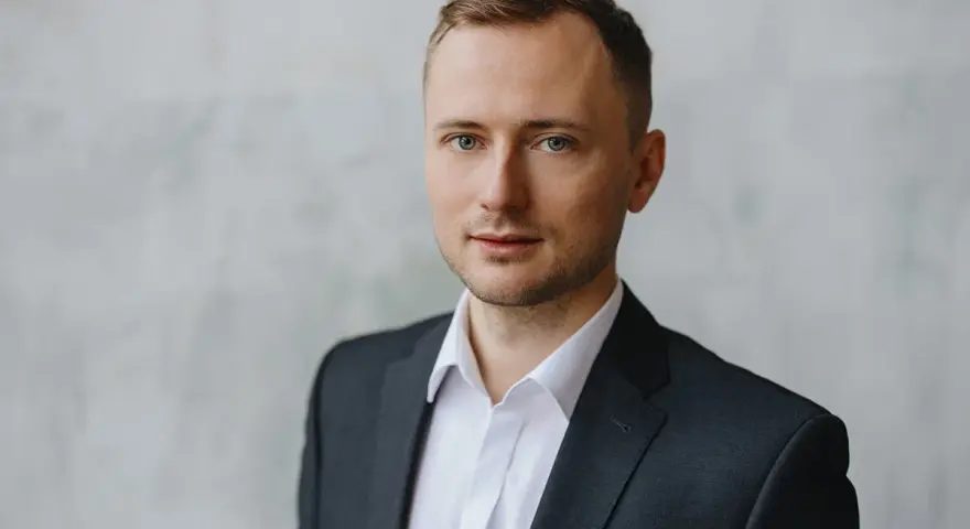 Mężczyzna w garniturze i białej koszuli, idealny przykład, jak zrobić zdjęcie biznesowe w domu.