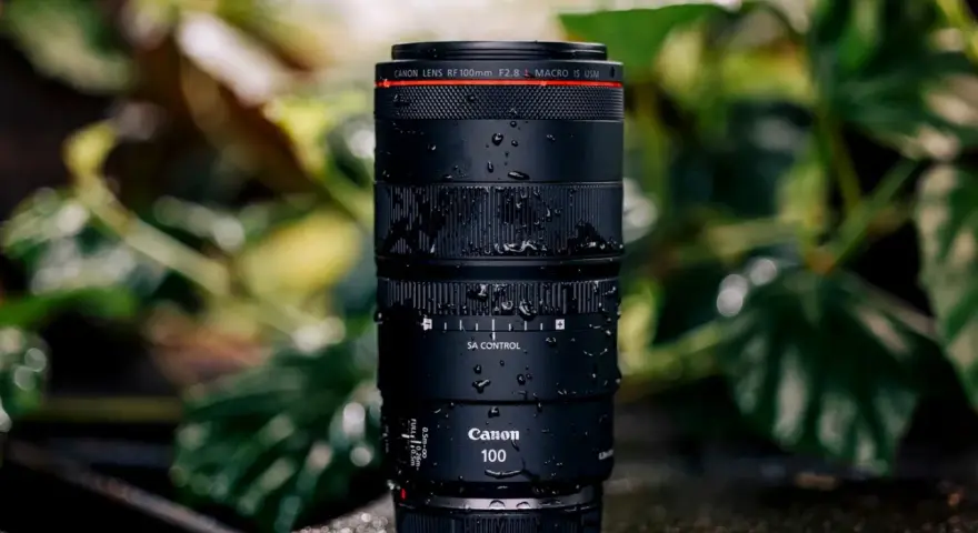 Objectif Canon RF 100mm f/2.8 Macro IS USM, couvert de gouttes d'eau, prêt pour un test en extérieur.