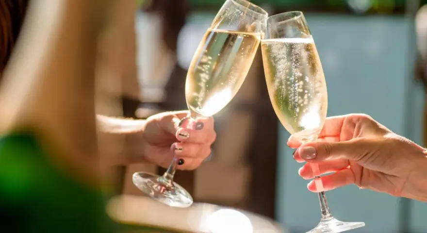 Zwei Hände stoßen mit Gläsern an, gefüllt mit prickelndem alkoholfreiem Sekt. Perfekt für die Schwangerschaft und besondere Anlässe.