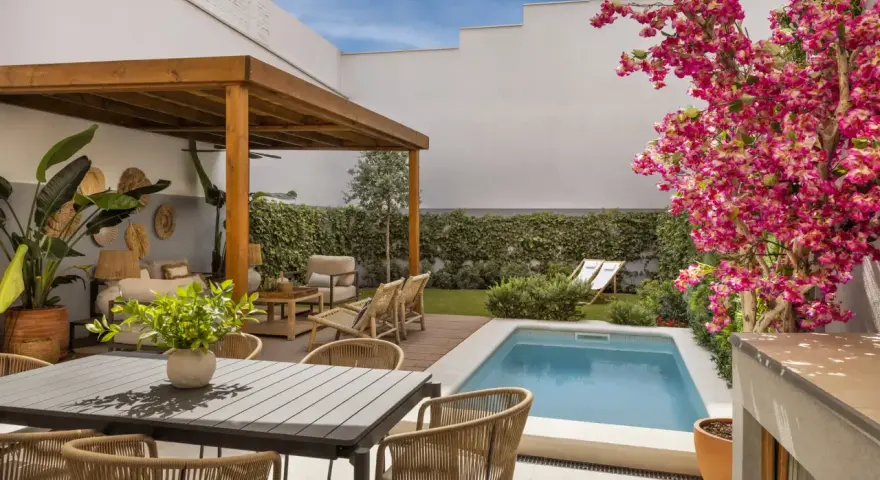 Un patio moderno con piscina, pérgola de madera, zona de estar y comedor exterior. Ideas para decorar un patio con piscina y crear un oasis de relax.