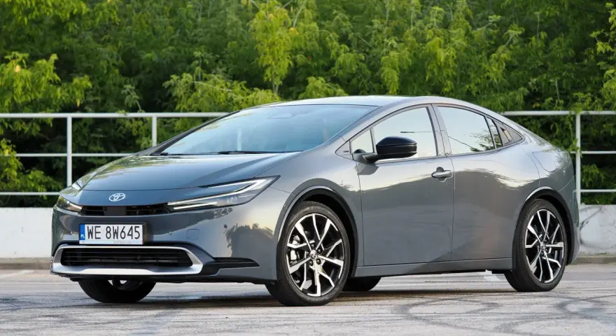 Szary Toyota Prius hybryda na tle zieleni. Zastanawiasz się, ile pali Toyota Prius hybryda? Ten model zachwyca niskim spalaniem.