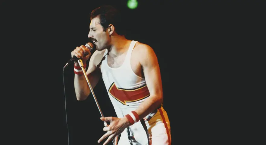 Freddie Mercury, jeden z najlepsi muzycy wszechczasów, śpiewa do mikrofonu na koncercie.