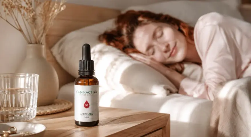 Una mujer duerme plácidamente. A su lado, en la mesita de noche, un frasco de aceite CBD, ideal para saber como tomar aceite de cbd para dormir y disfrutar de un descanso reparador.