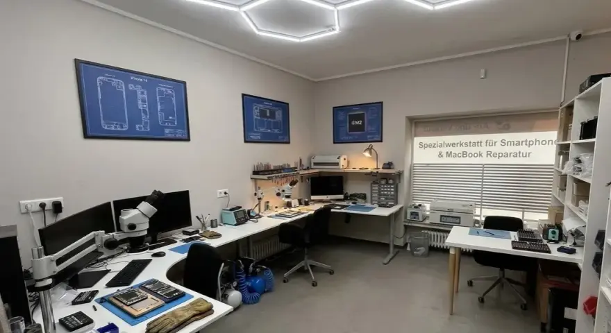 Werkstatt für Smartphone- und MacBook-Reparatur mit Werkzeugen, Mikroskop und technischen Zeichnungen.