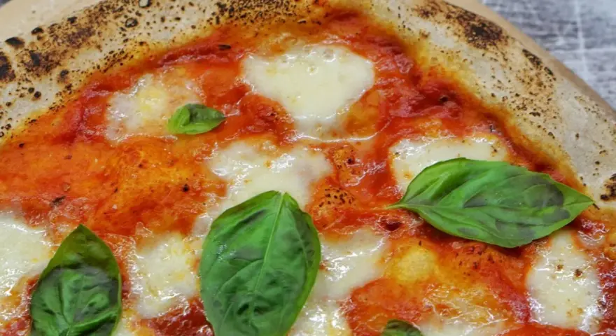 Ein Stück italienische Pizza Margherita mit geschmolzenem Mozzarella, Tomatensauce und frischem Basilikum. Perfekt für ein authentisches italien pizza rezept.