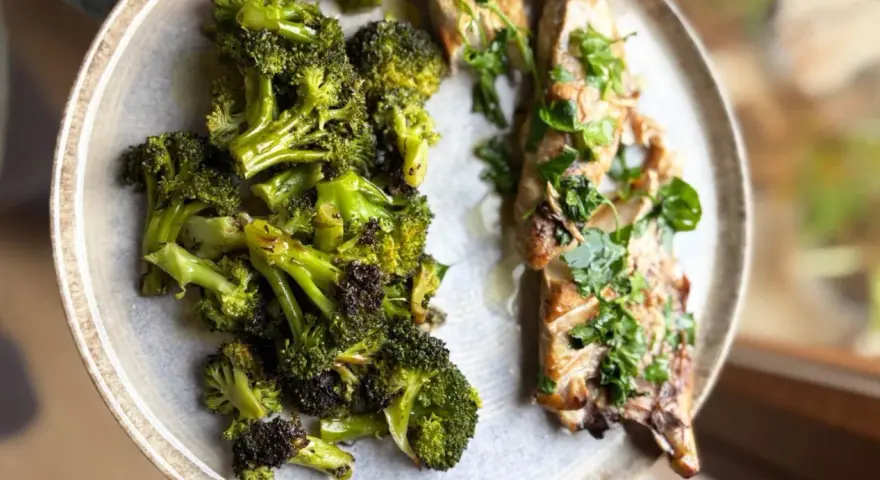 Brocoli al horno, tierno y dorado, junto a un filete de pescado con hierbas frescas.