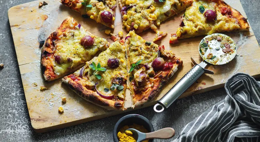 Domowa pizza z kurczakiem, kukurydzą i czerwoną cebulą, pokrojona na kawałki, gotowa do podania.