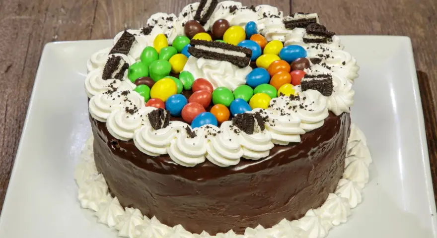 Torta al cioccolato con panna, caramelle colorate e biscotti Oreo, un'esplosione di gusto per torte di compleanno particolari.