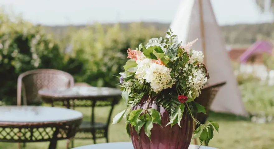 Un hermoso arreglo de flores en un jarrón morado, perfecto para celebrar un feliz día del Carmen.
