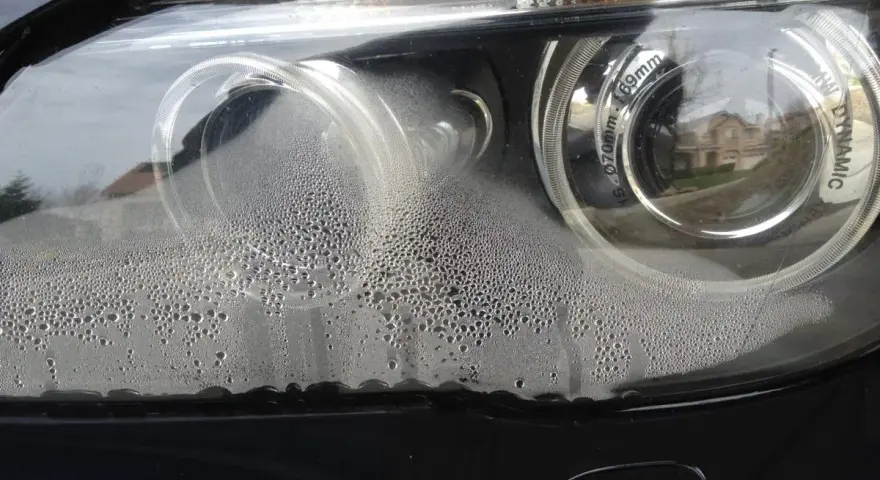 Krople wody wewnątrz reflektora BMW. Brak widocznych odpowietrzników w reflektorach sugeruje problem z uszczelnieniem.