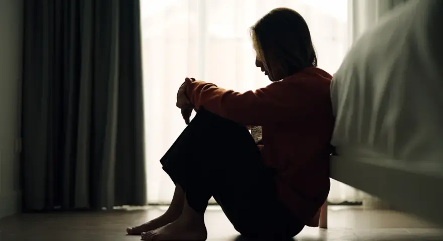 Ein Mädchen sitzt traurig auf dem Boden, die Knie angezogen. Die Szene könnte die emotionale Achterbahnfahrt bei borderline bei Kindern darstellen.